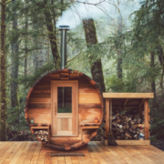 Forest Cooperage Cedar Barrel Sauna set in the forest with smoke coming from the heater with a damp and earth look.